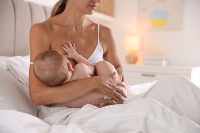 Photo of Mother breastfeeding her little baby indoors, closeup