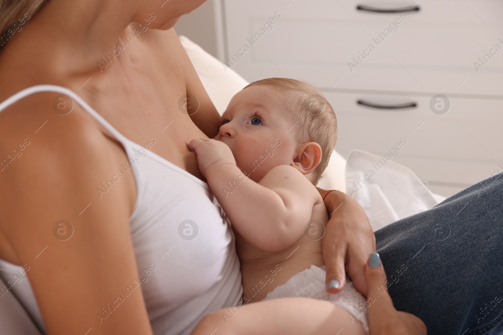 Photo of Mother breastfeeding her little baby indoors, closeup