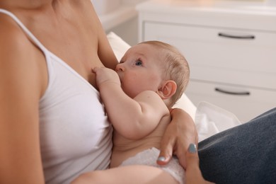 Photo of Mother breastfeeding her little baby indoors, closeup