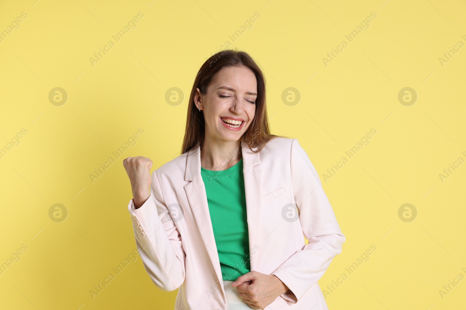 Photo of Portrait of happy winner on yellow background