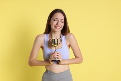 Photo of Happy winner with gold trophy cup on yellow background