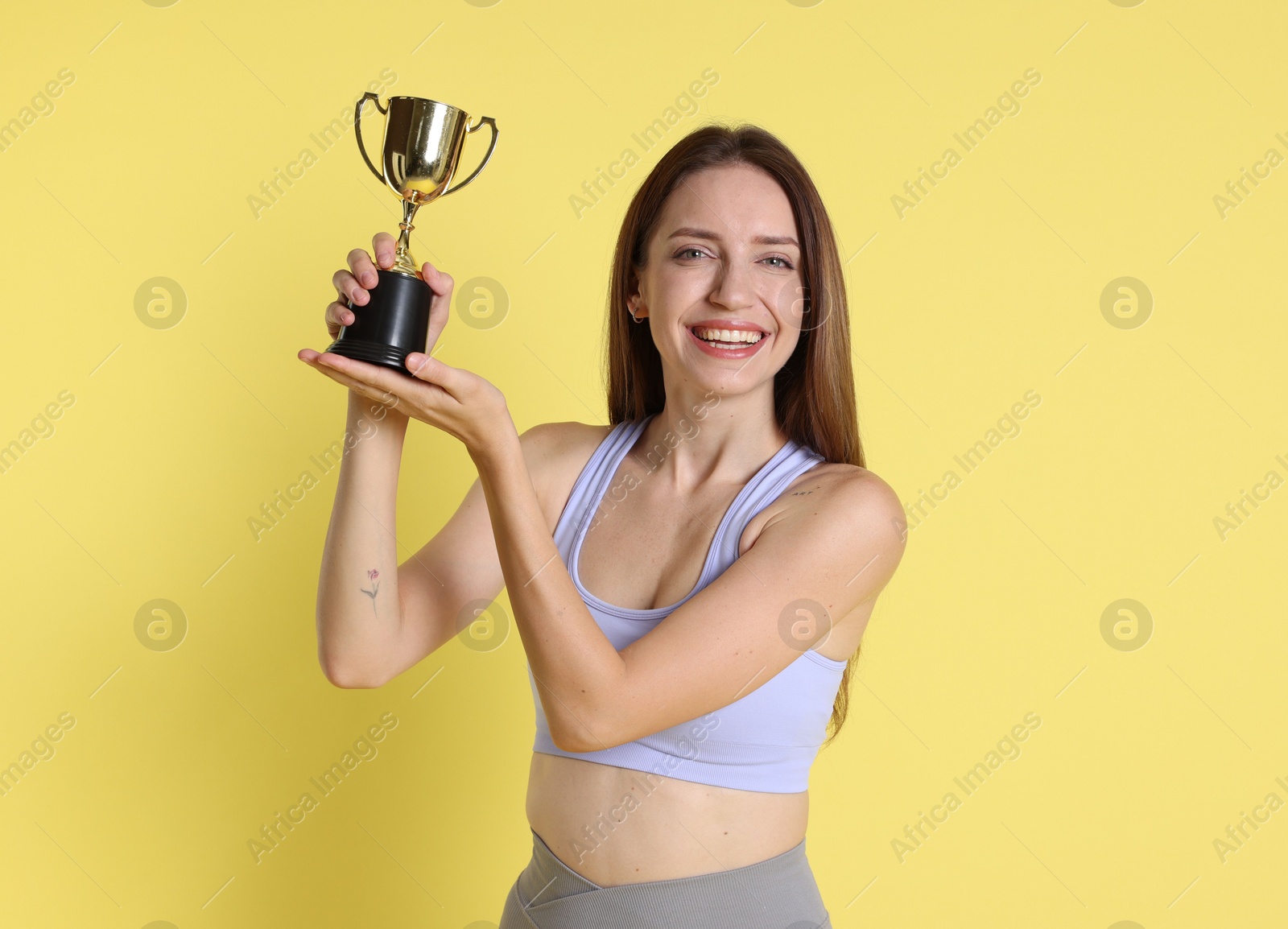 Photo of Happy winner with gold trophy cup on yellow background