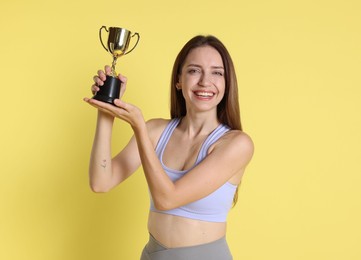 Photo of Happy winner with gold trophy cup on yellow background