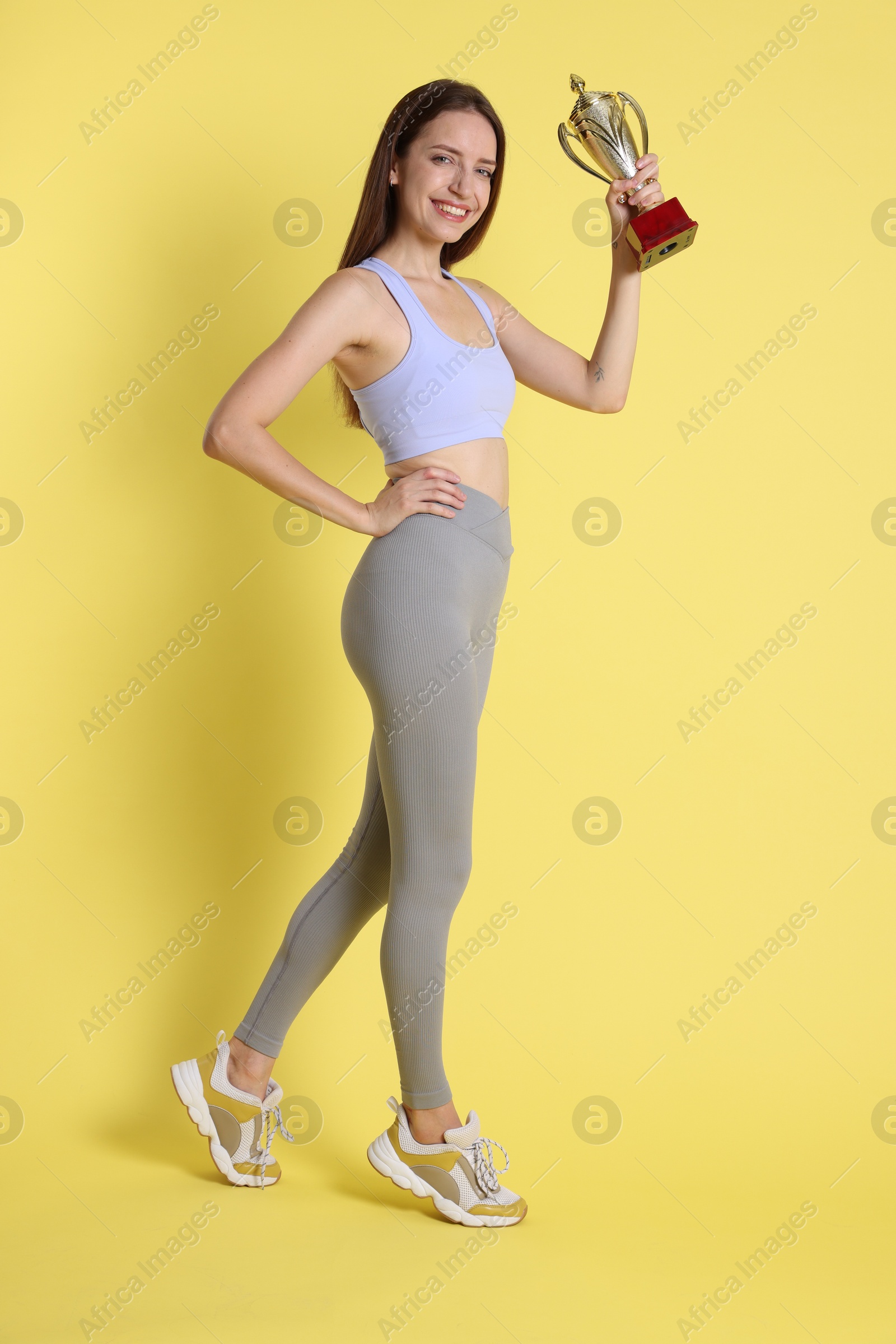 Photo of Happy winner with gold trophy cup on yellow background