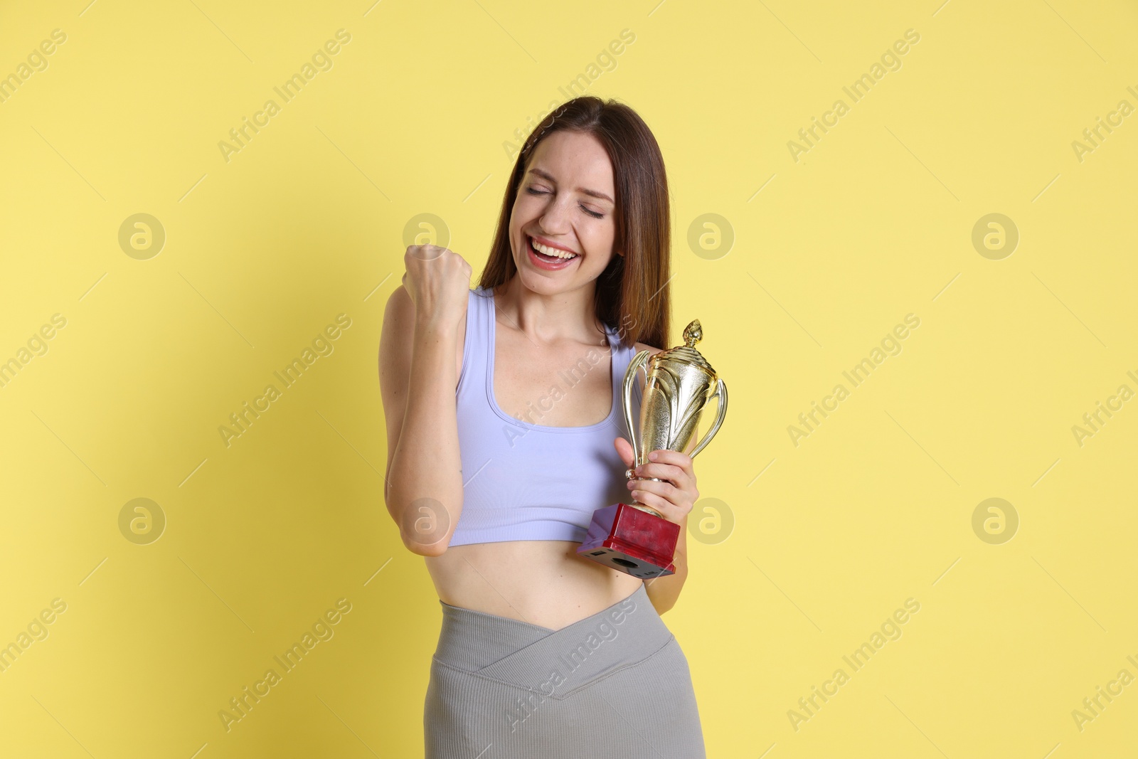 Photo of Happy winner with gold trophy cup on yellow background