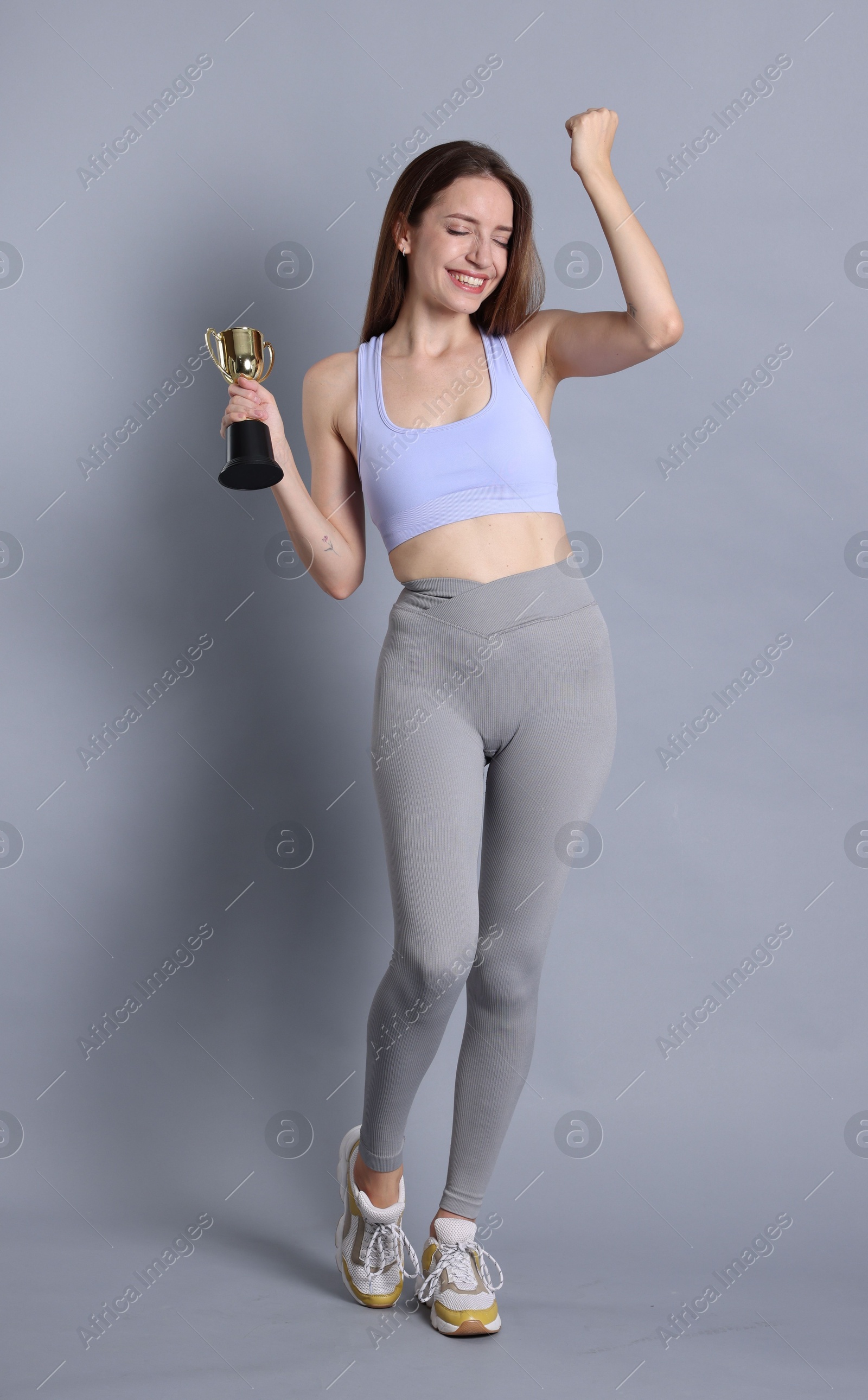 Photo of Happy winner with gold trophy cup on gray background