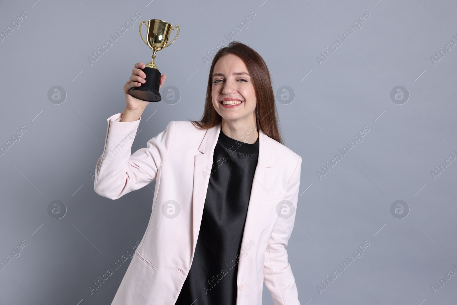 Photo of Happy winner with gold trophy cup on gray background