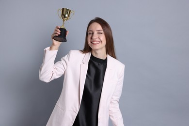 Happy winner with gold trophy cup on gray background