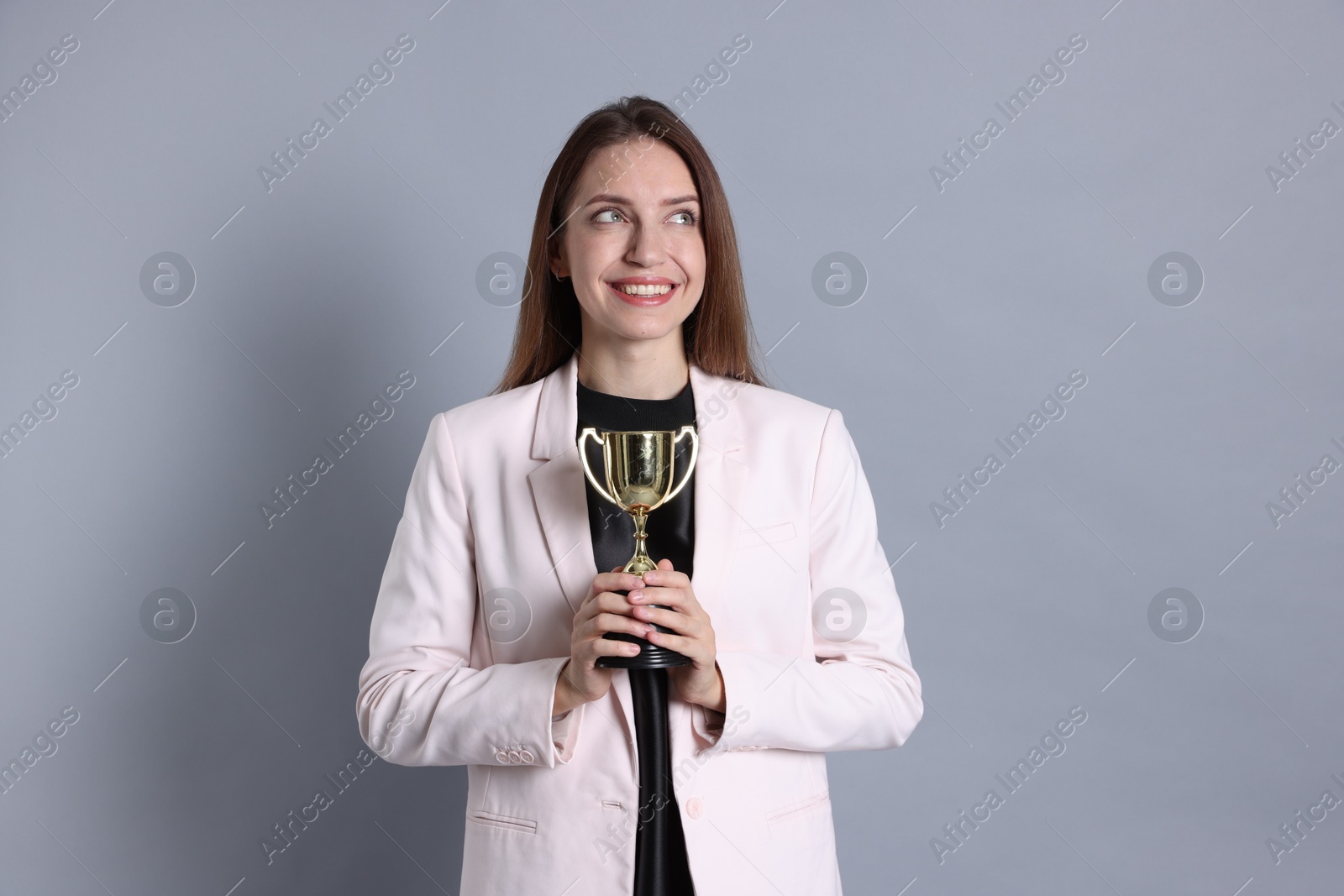 Photo of Happy winner with gold trophy cup on gray background