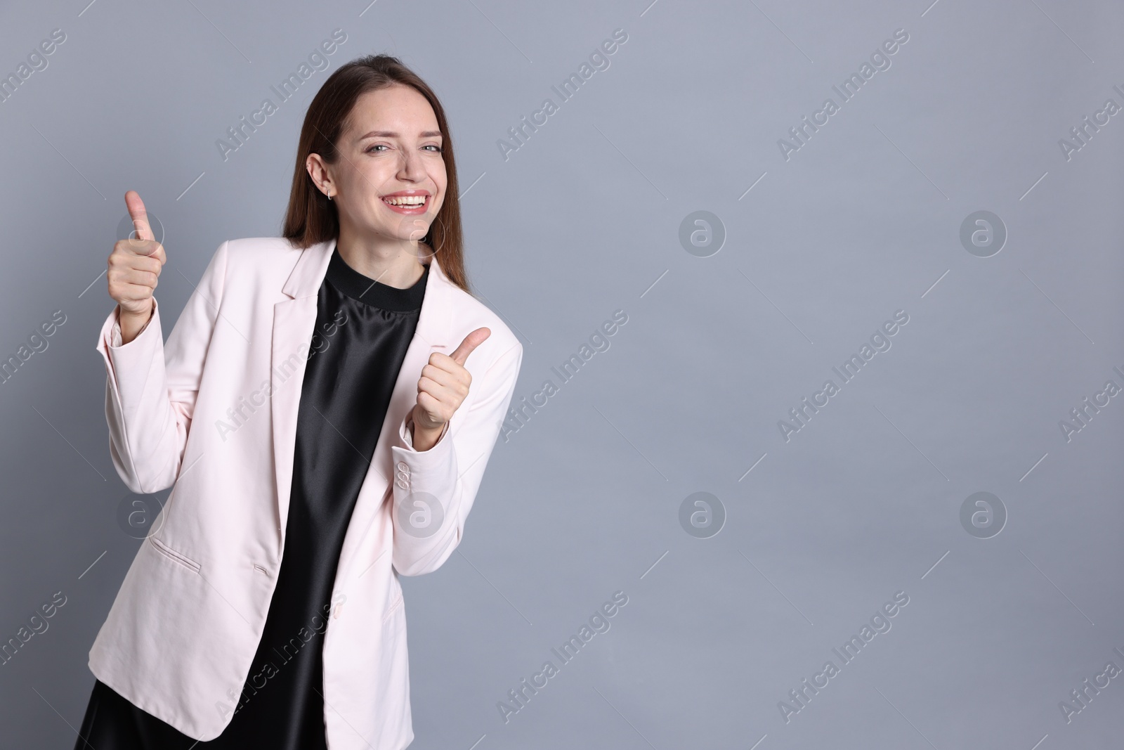 Photo of Happy winner showing thumbs up on gray background, space for text