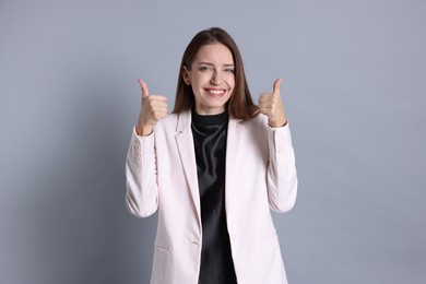 Happy winner showing thumbs up on gray background