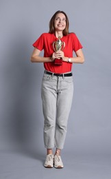 Photo of Happy winner with gold trophy cup on gray background