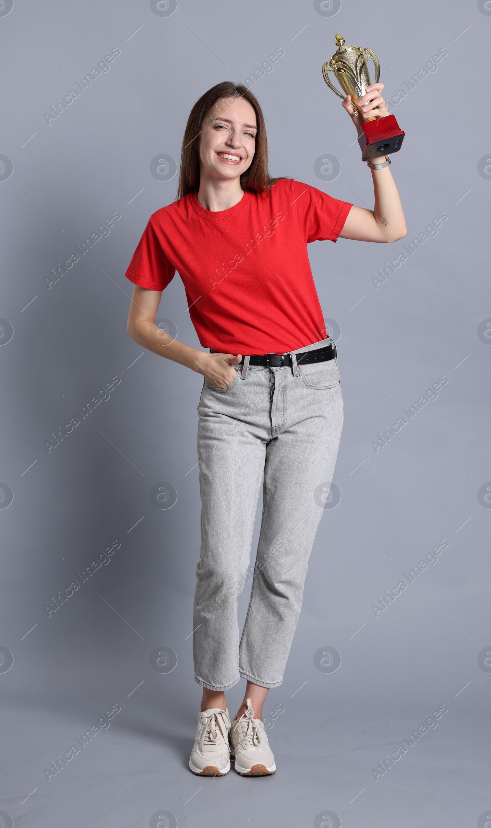 Photo of Happy winner with gold trophy cup on gray background