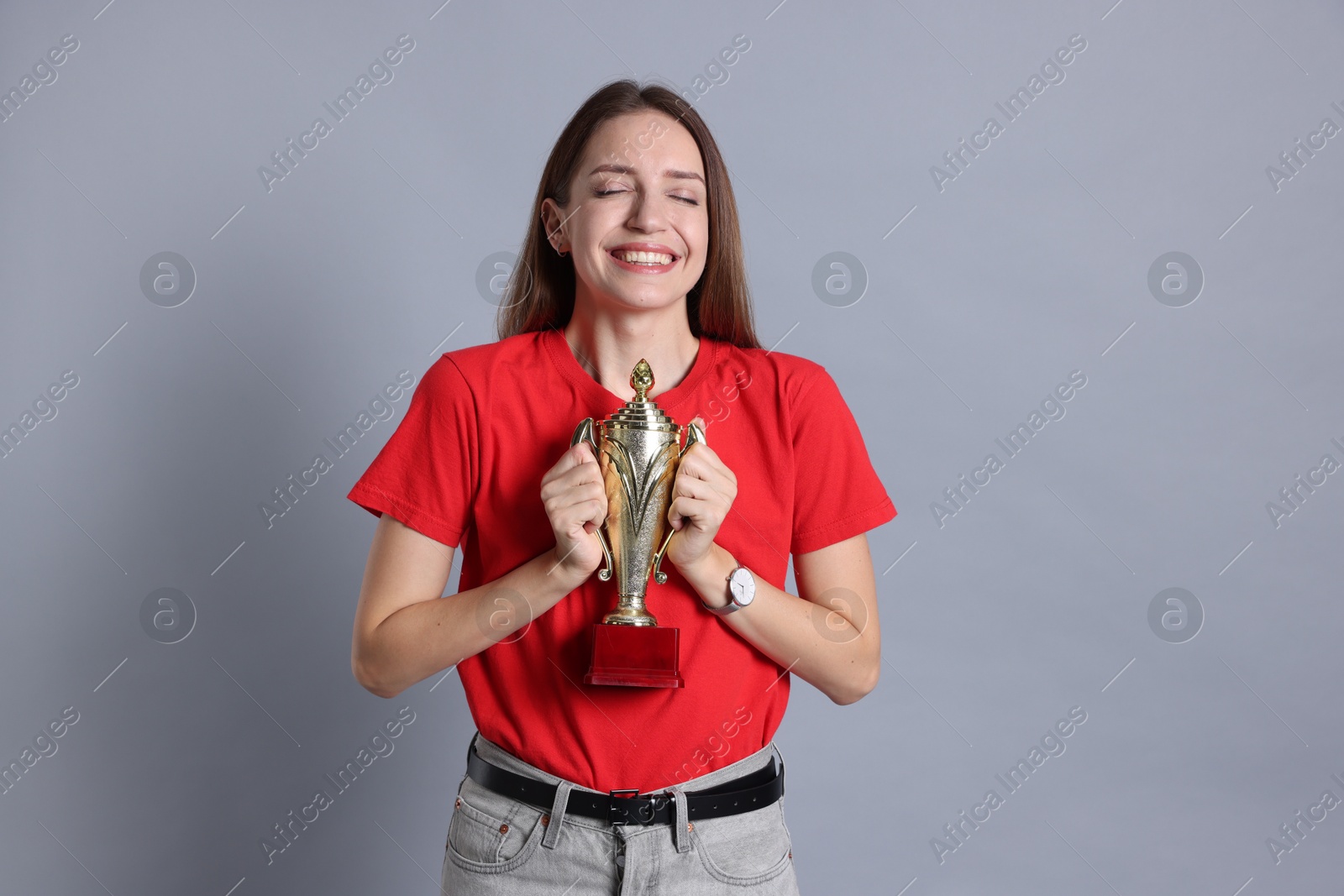 Photo of Happy winner with gold trophy cup on gray background