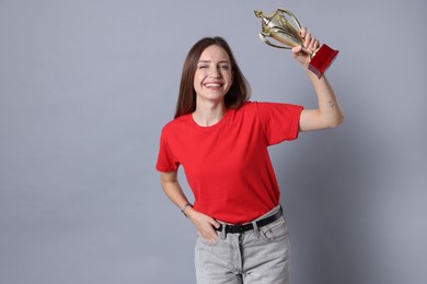 Photo of Happy winner with gold trophy cup on gray background