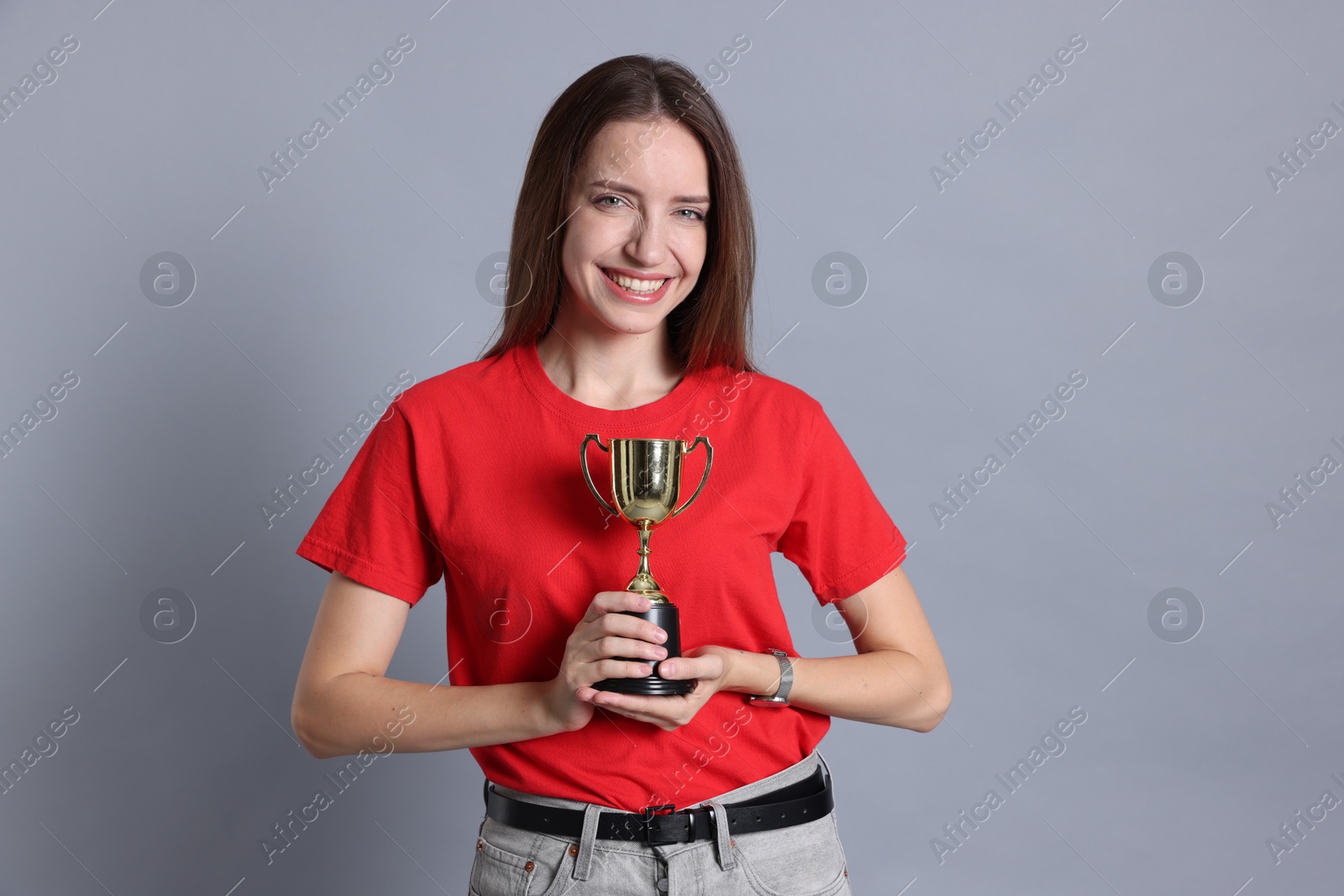 Photo of Happy winner with gold trophy cup on gray background