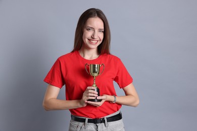 Happy winner with gold trophy cup on gray background