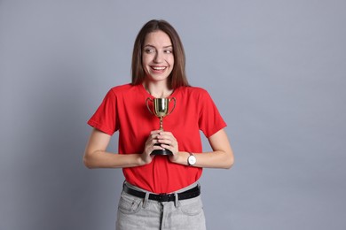 Happy winner with gold trophy cup on gray background