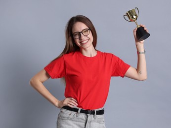 Happy winner with gold trophy cup on gray background