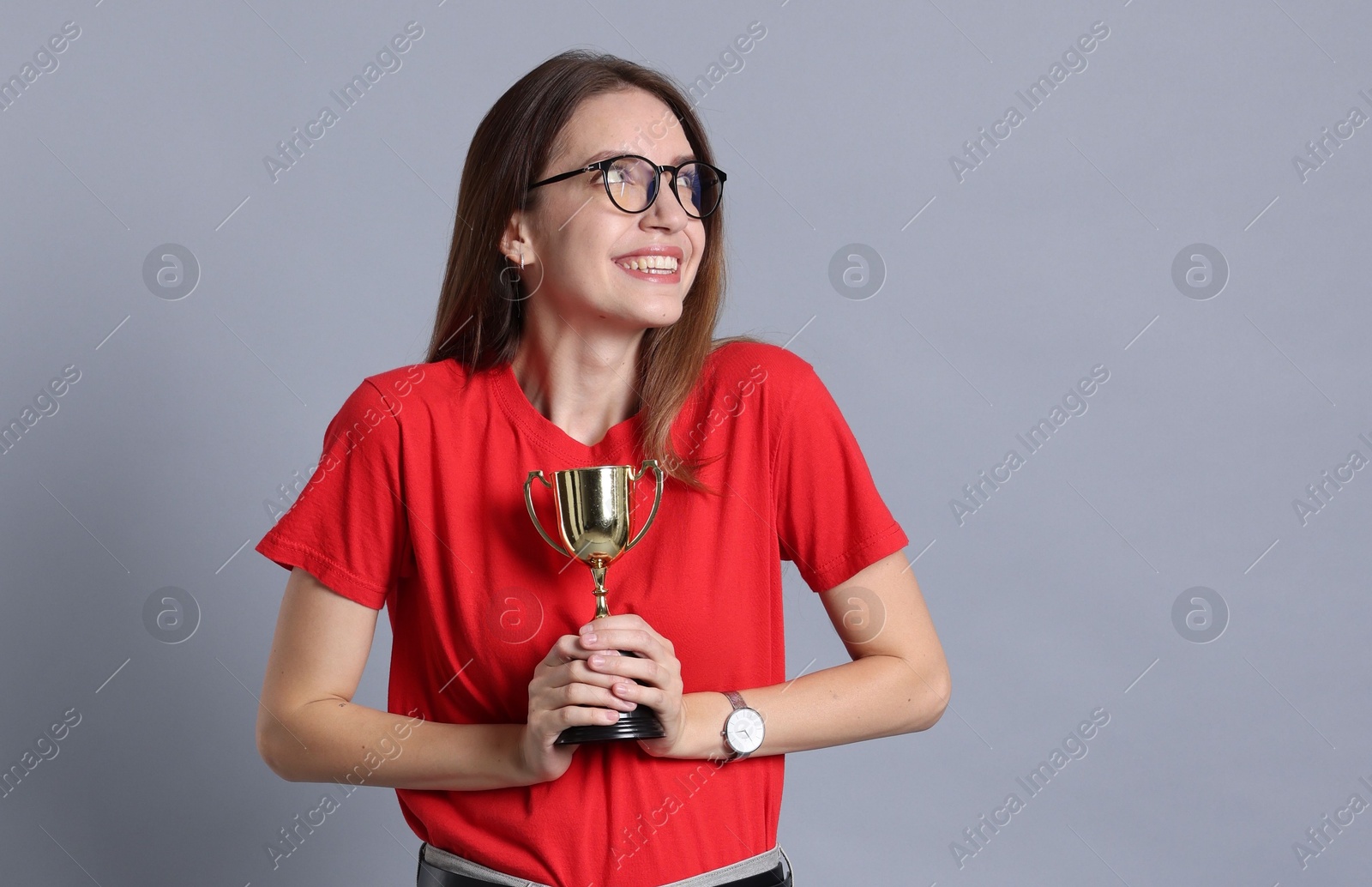 Photo of Happy winner with gold trophy cup on gray background