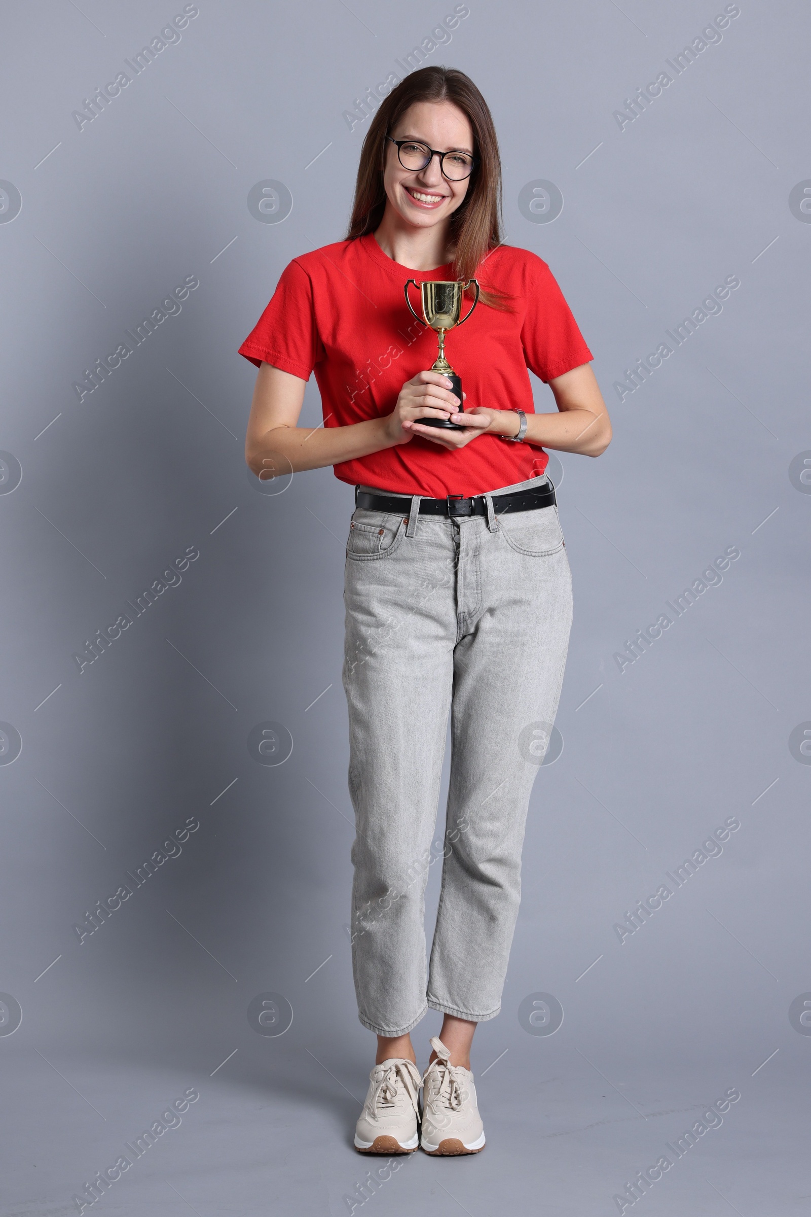 Photo of Happy winner with gold trophy cup on gray background