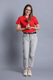 Photo of Happy winner with gold trophy cup on gray background