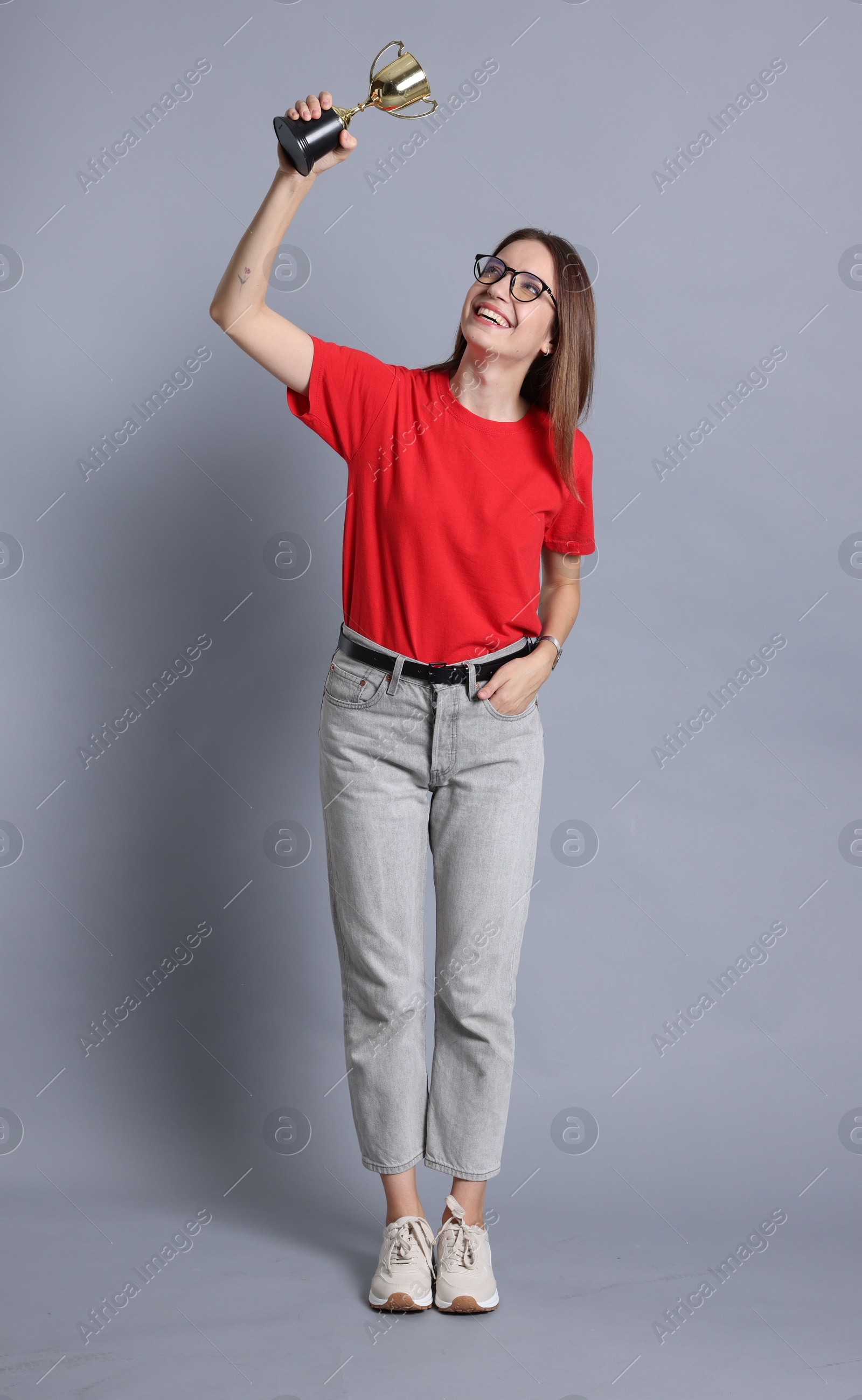 Photo of Happy winner with gold trophy cup on gray background