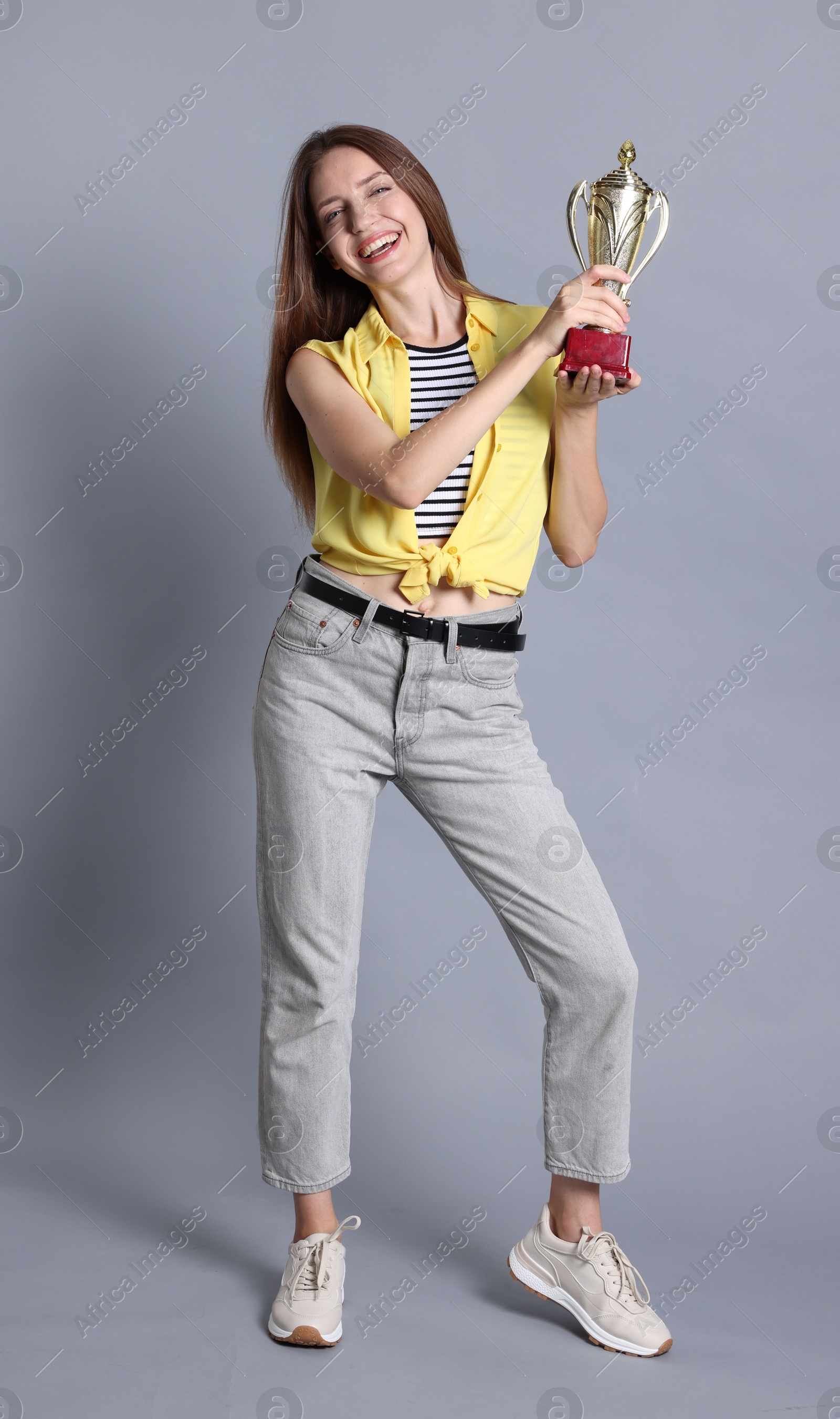 Photo of Happy winner with gold trophy cup on gray background