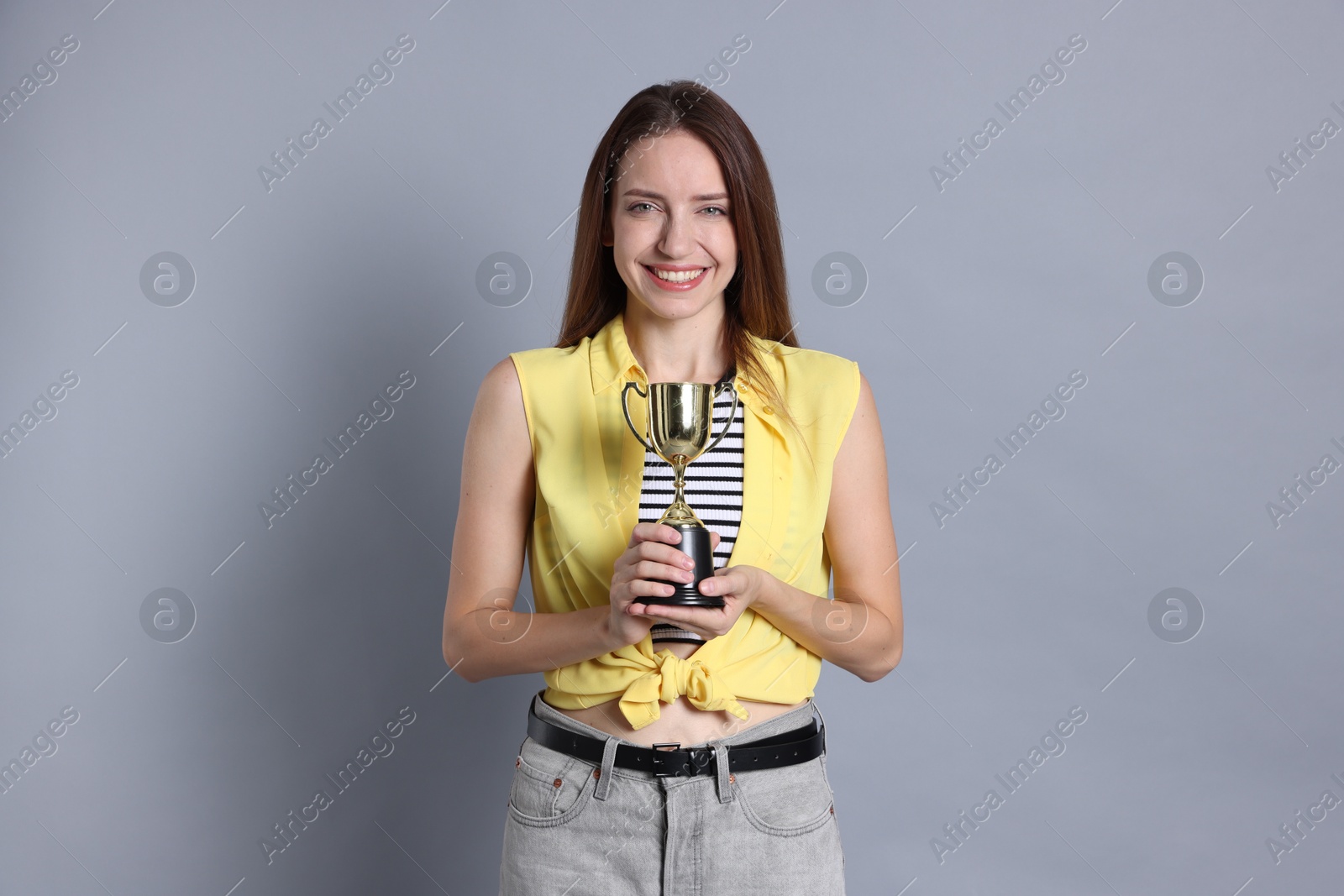 Photo of Happy winner with gold trophy cup on gray background