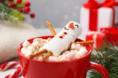 Photo of Funny snowman made with marshmallows in cup of hot drink and Christmas decor, closeup