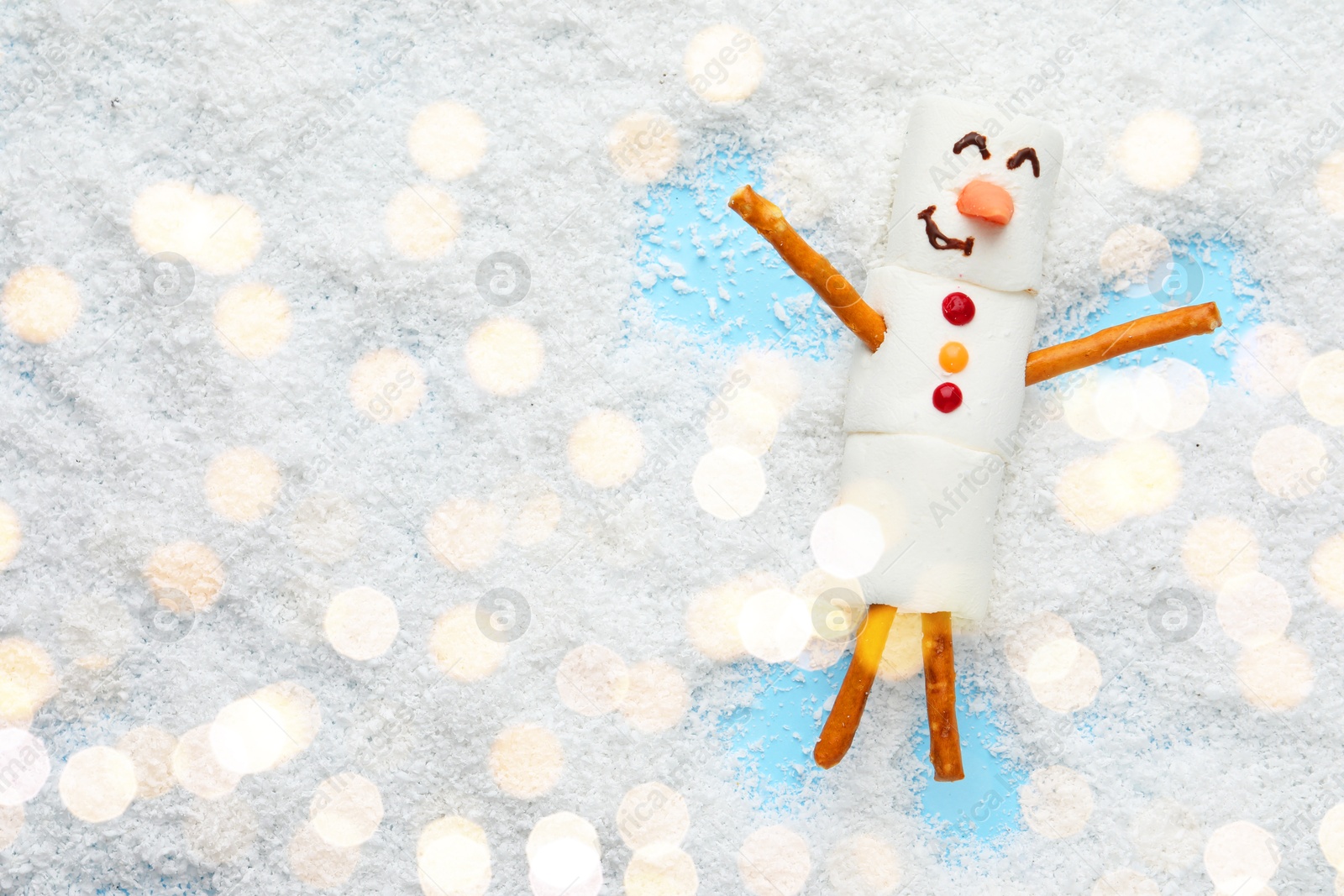 Photo of Marshmallow snowman making angel on artificial snow, top view. Space for text