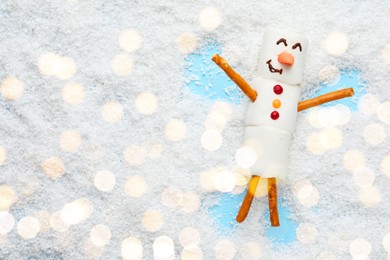 Photo of Marshmallow snowman making angel on artificial snow, top view. Space for text