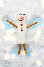 Photo of Marshmallow snowman making angel on artificial snow, top view