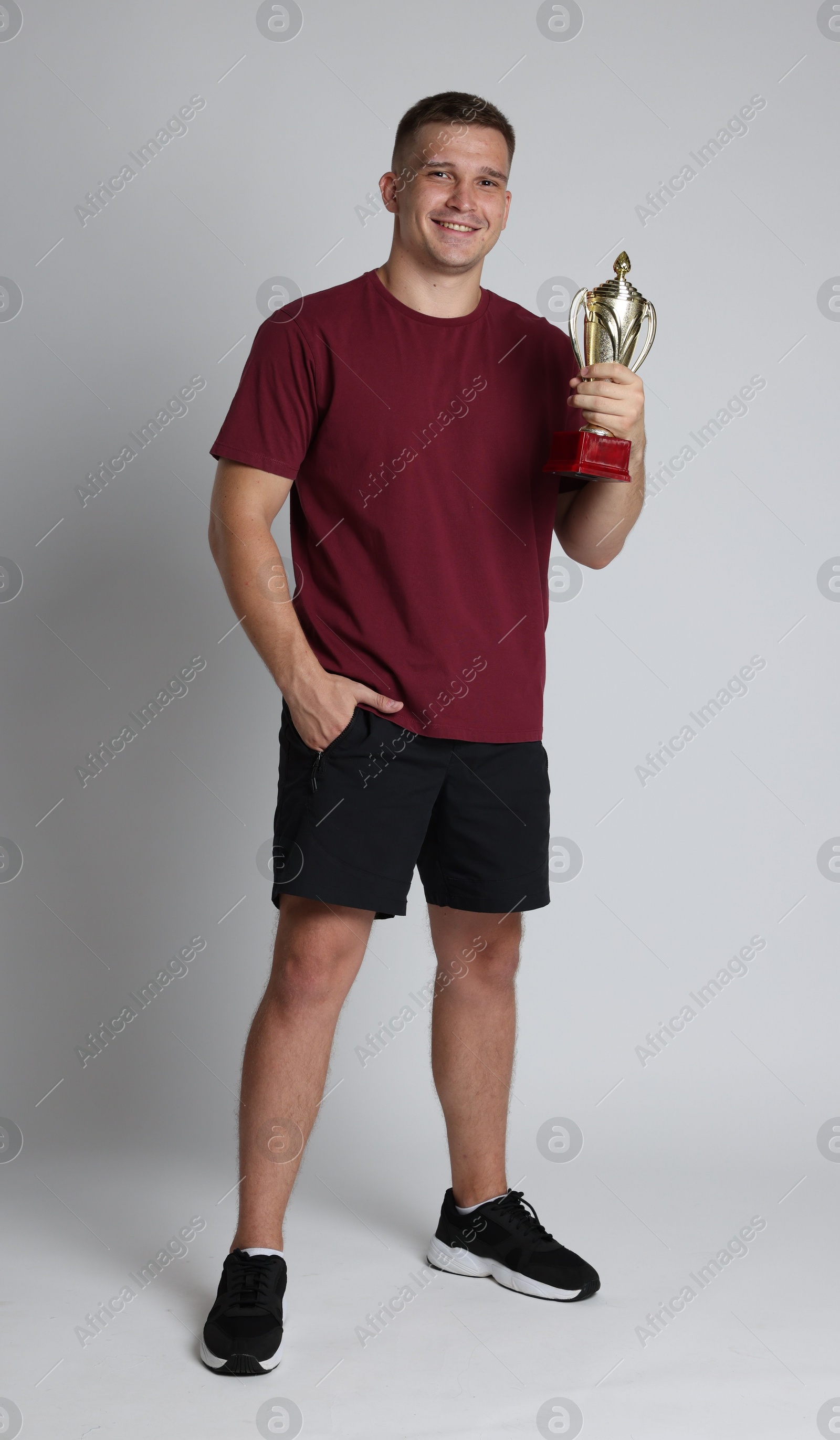 Photo of Happy winner with golden trophy cup on light grey background