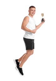 Photo of Happy winner with golden trophy cup jumping on white background