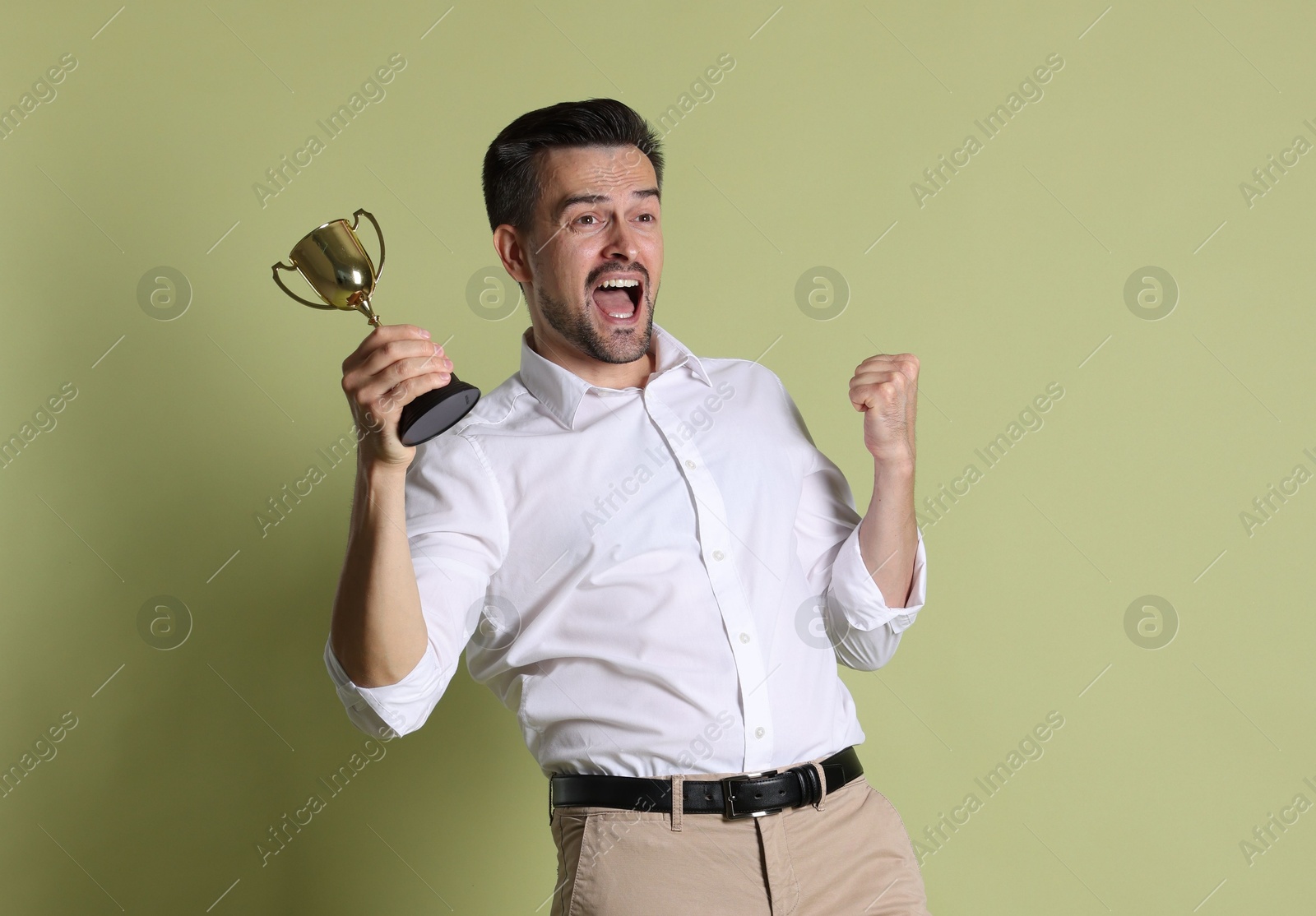 Photo of Happy winner with golden trophy cup on pale olive background