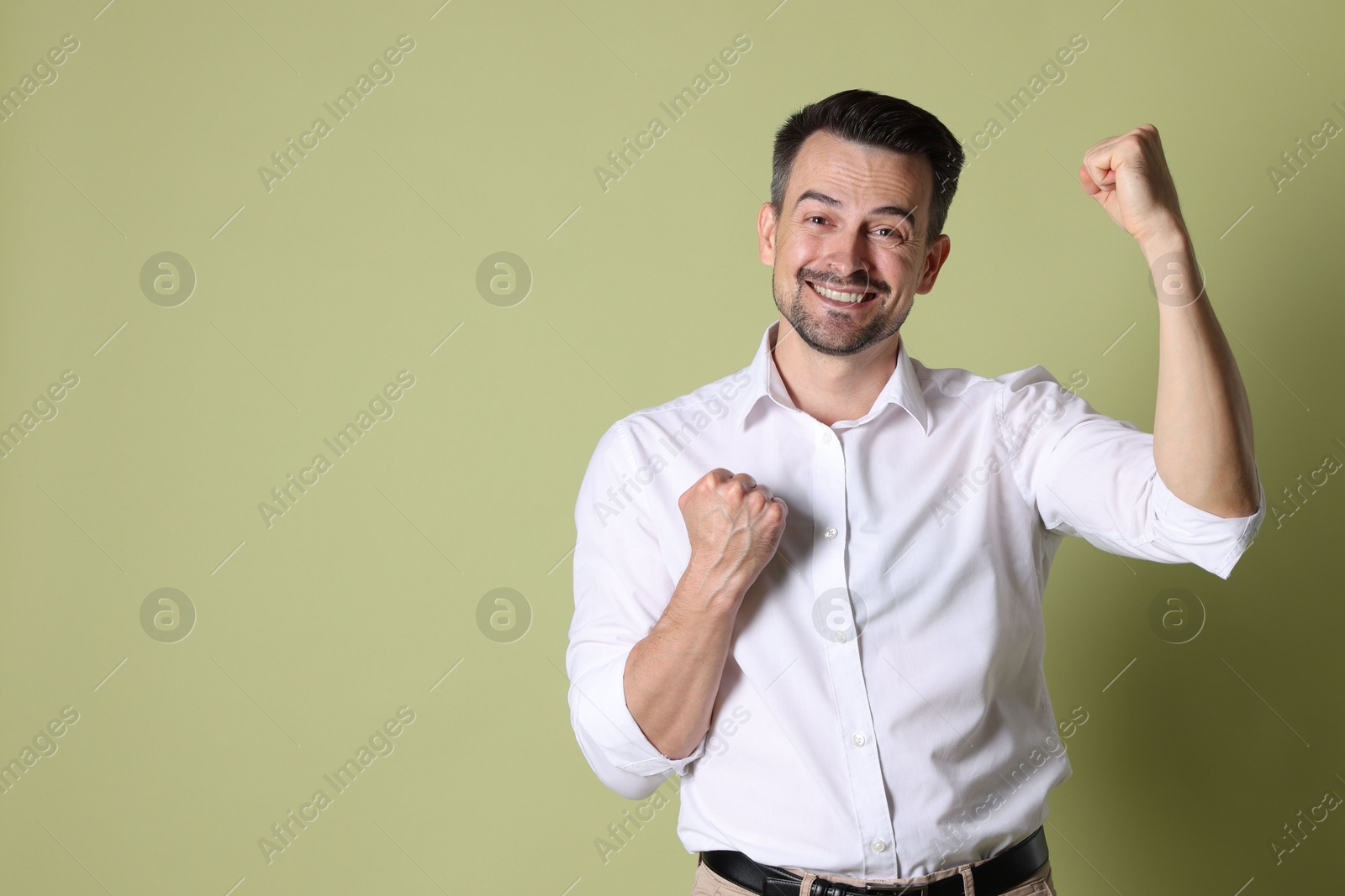 Photo of Portrait of happy winner on pale olive background, space for text