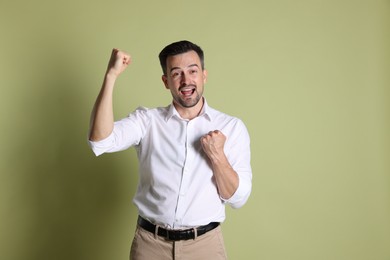 Photo of Portrait of happy winner on pale olive background