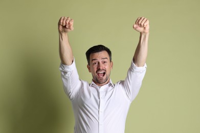 Portrait of happy winner on pale olive background