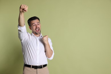 Portrait of happy winner on pale olive background, space for text