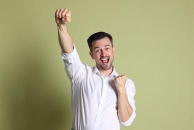 Photo of Portrait of happy winner on pale olive background