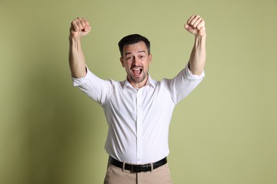 Portrait of happy winner on pale olive background