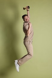 Happy winner with golden trophy cup jumping on pale olive background