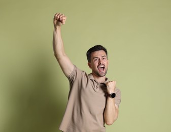 Portrait of happy winner on pale olive background