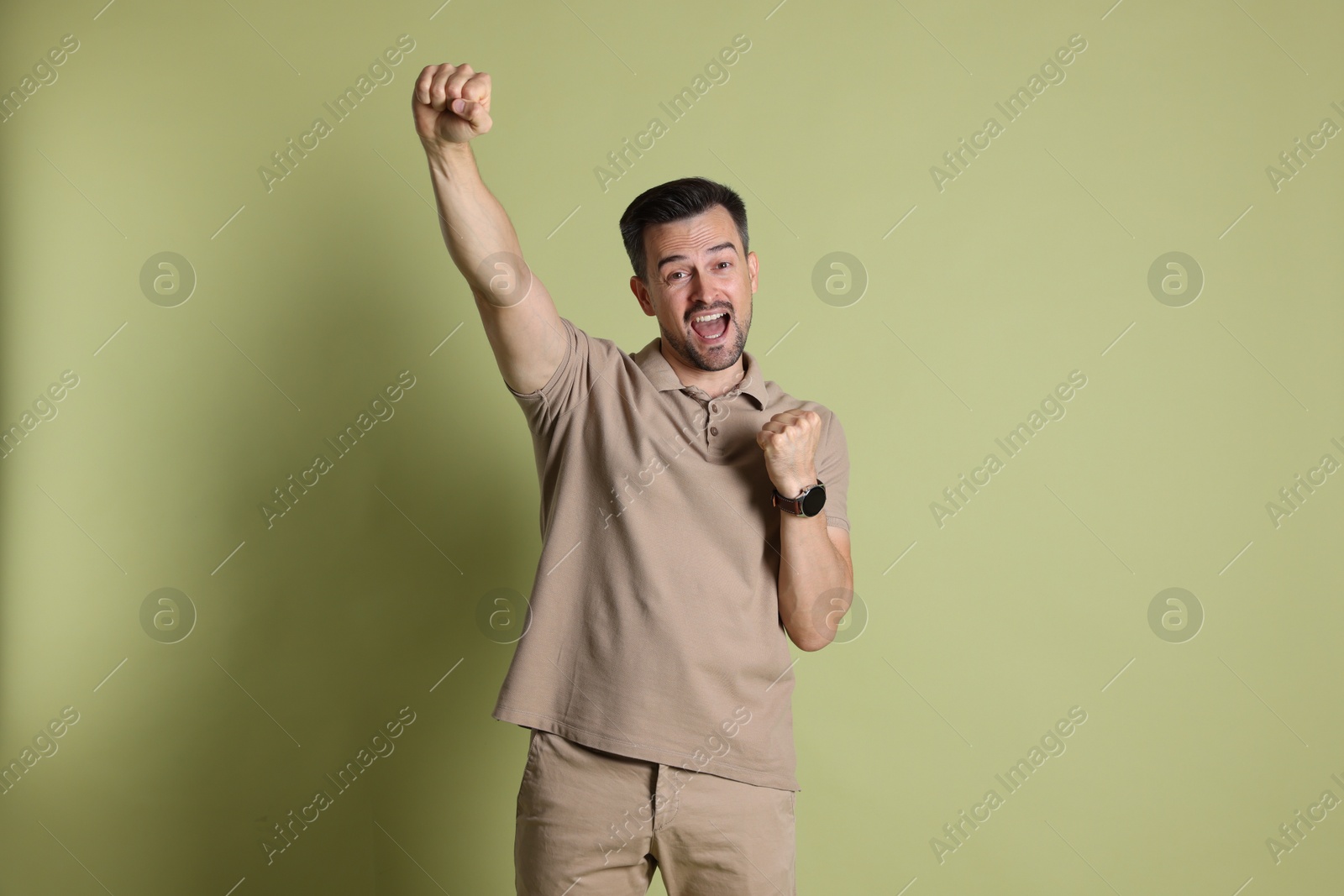 Photo of Portrait of happy winner on pale olive background