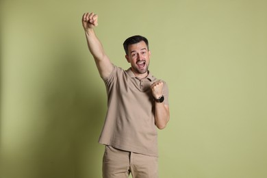 Portrait of happy winner on pale olive background