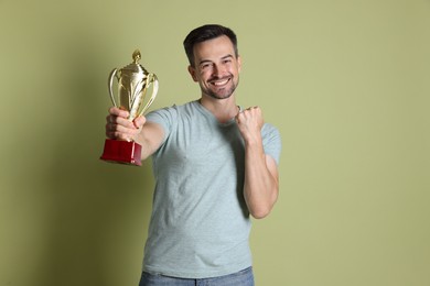 Happy winner with golden trophy cup on pale olive background