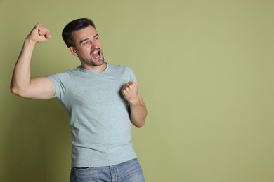 Photo of Portrait of happy winner on pale olive background, space for text