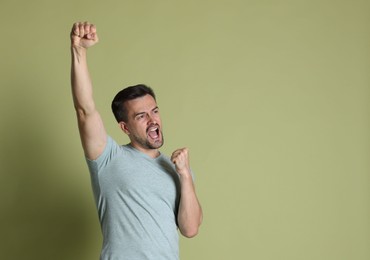 Portrait of happy winner on pale olive background, space for text