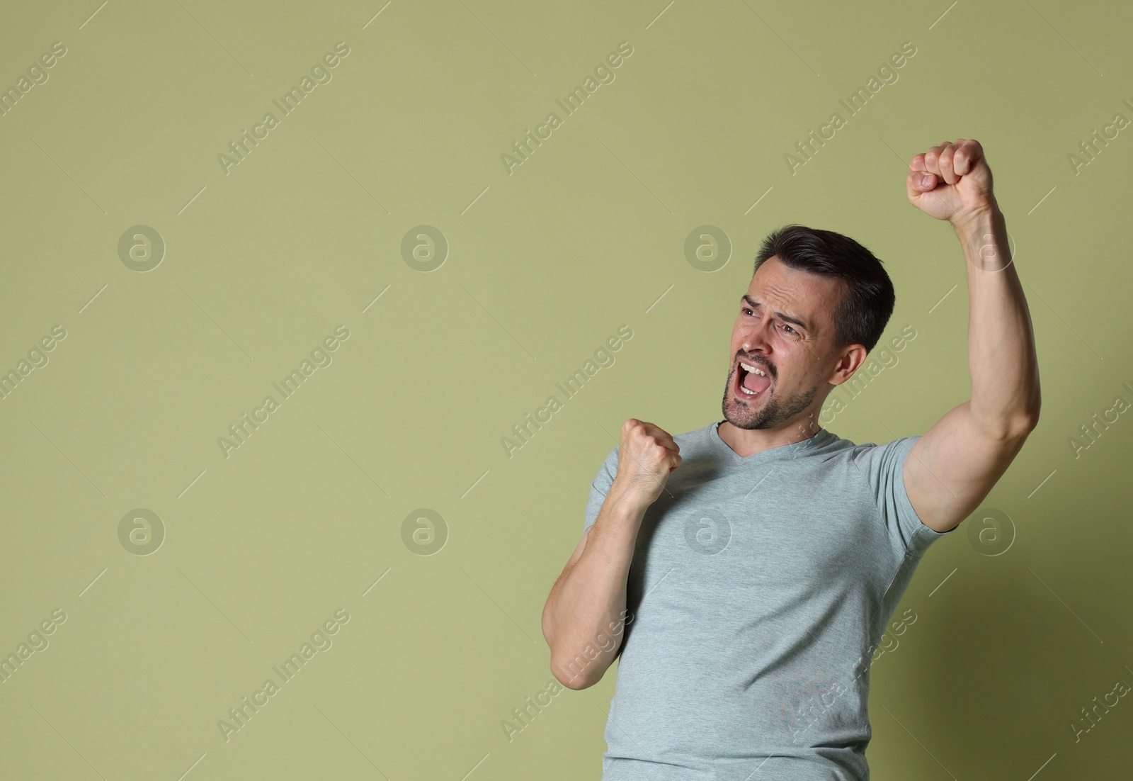 Photo of Portrait of happy winner on pale olive background, space for text